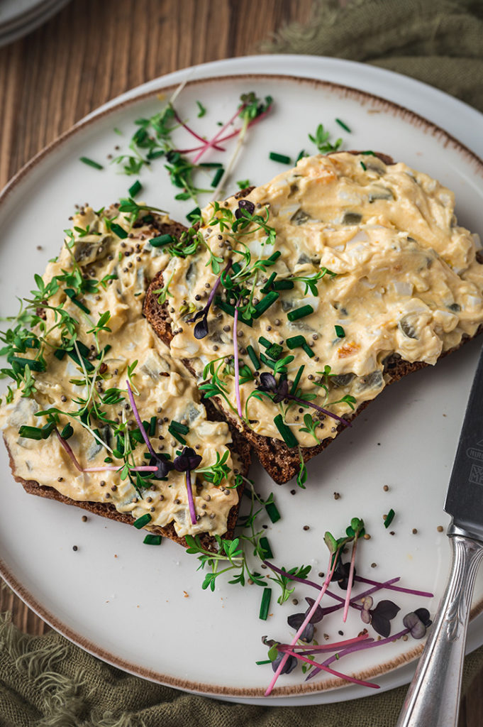 Eine Nahaufnahme von einem Brot mit Eieraufstrich belegt.