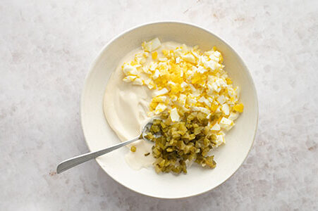 Die klein geschnittenen Cornichons und Eier wurden zu dem Frischkäse gegeben.