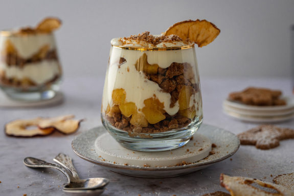 Ein Glas mit einem Spekulatius Bratapfel Dessert steht auf einem Tisch