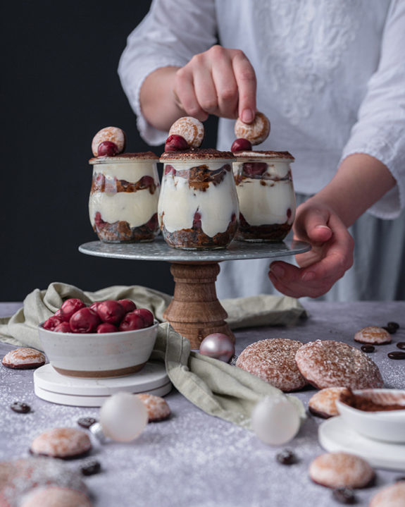 Eine Frau verziert das Lebkuchen Tiramisu mit kleinen Lebkuchen-Talern.