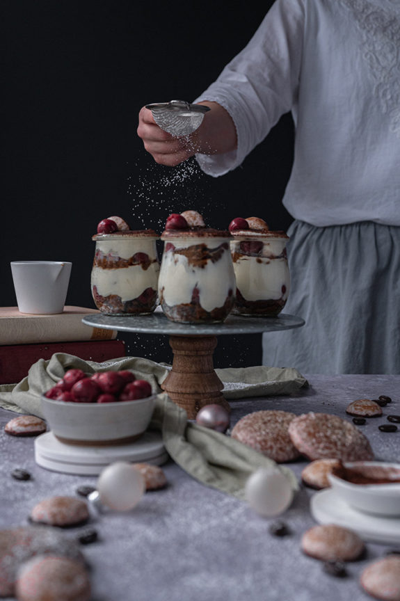 Eine Frau streut Puderzucker über das Lebkuchen Tiramisu.