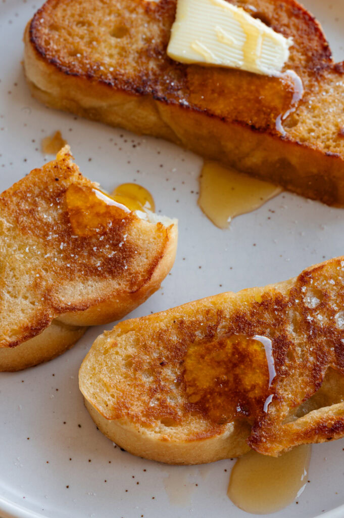 Eine Nahaufnahme von drei Scheiben Arme Ritter ohne Ei mit Ahornsirup.