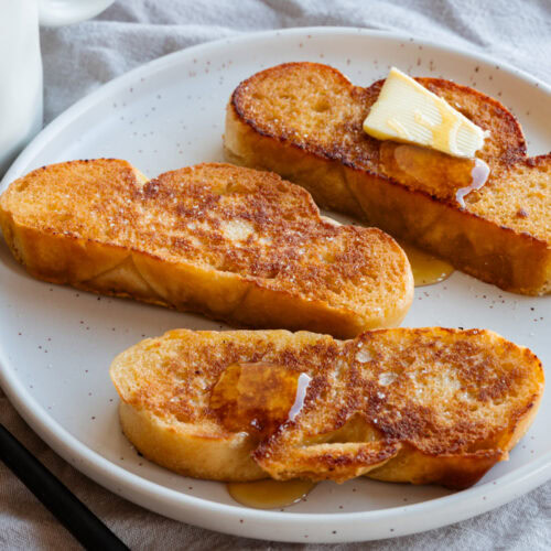 Ein Teller mit drei Scheiben Arme Ritter ohne Ei und etwas Ahornsirup.