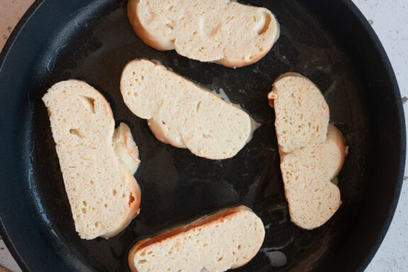 5 Scheiben Brot werden in einer Pfanne angebraten.