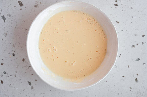 Eine Schüssel mit Puddingpulver und Milch steht auf einem Tisch.