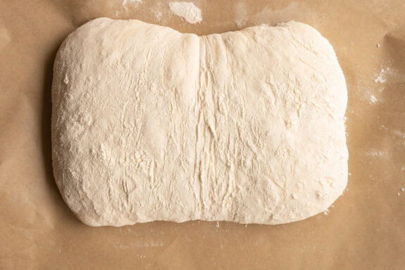 Ein rohes Ciabatta liegt auf einem Backpapier.