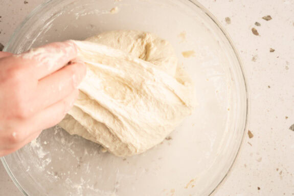 Eine Person faltet den Teig in die Mitte.