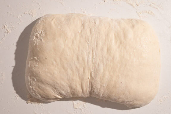 Ein geformtes Ciabatta liegt auf einer Arbeitsfläche.
