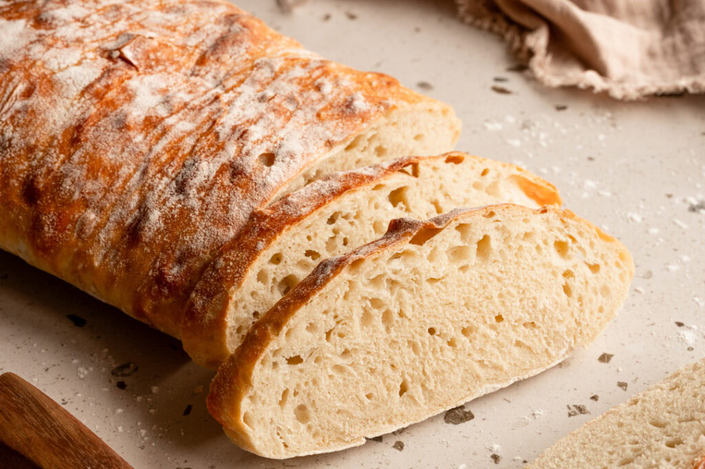 Ein angeschnittenes Ciabatta liegt auf einer Arbeitsfläche.