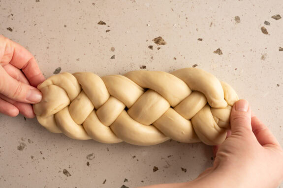 Eine Person drückt die Enden des Zopfs zusammen.