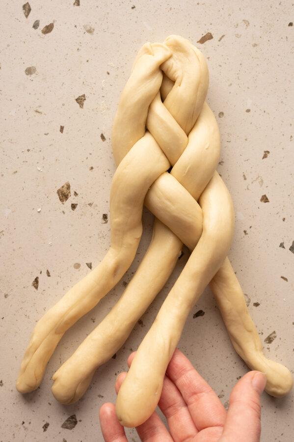 Eine Person flechtet den Zopf mit 4 Strängen.