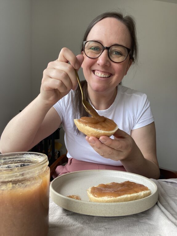 Eine Frau schmiert ihr Brötchen mit Rhabarber Marmelade.