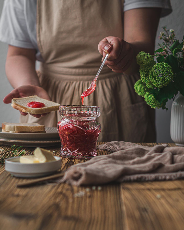 Eine Frau gibt Marmelade auf ein Toast.