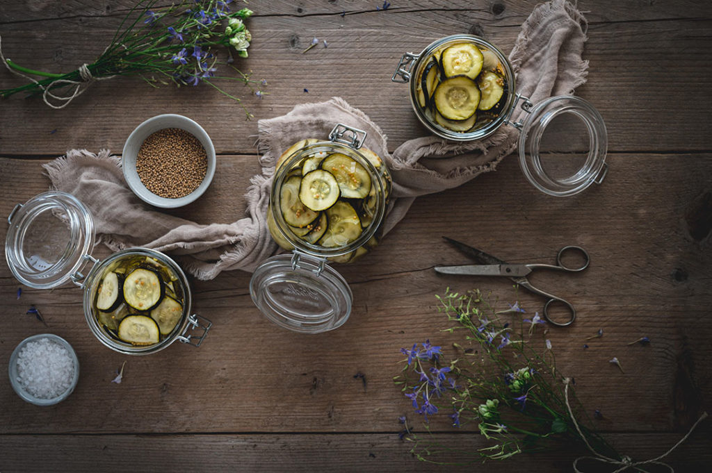 Drei Weckgläser mit eingelegten Zucchini auf einem Tisch