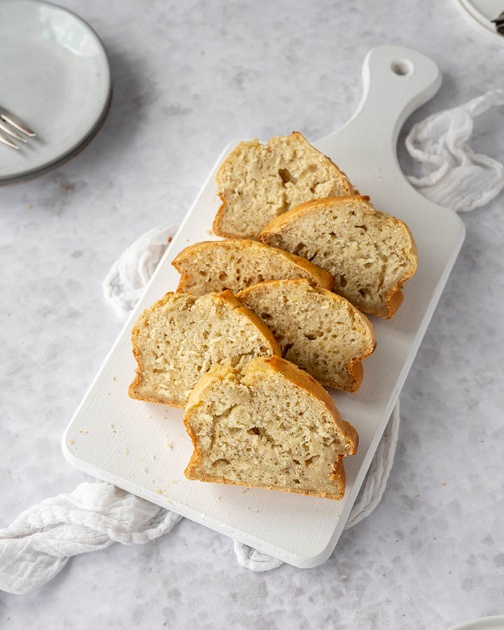 Das Bananenbrot aus 2 Bananen liegt in Scheiben geschnitten auf einen Brett.