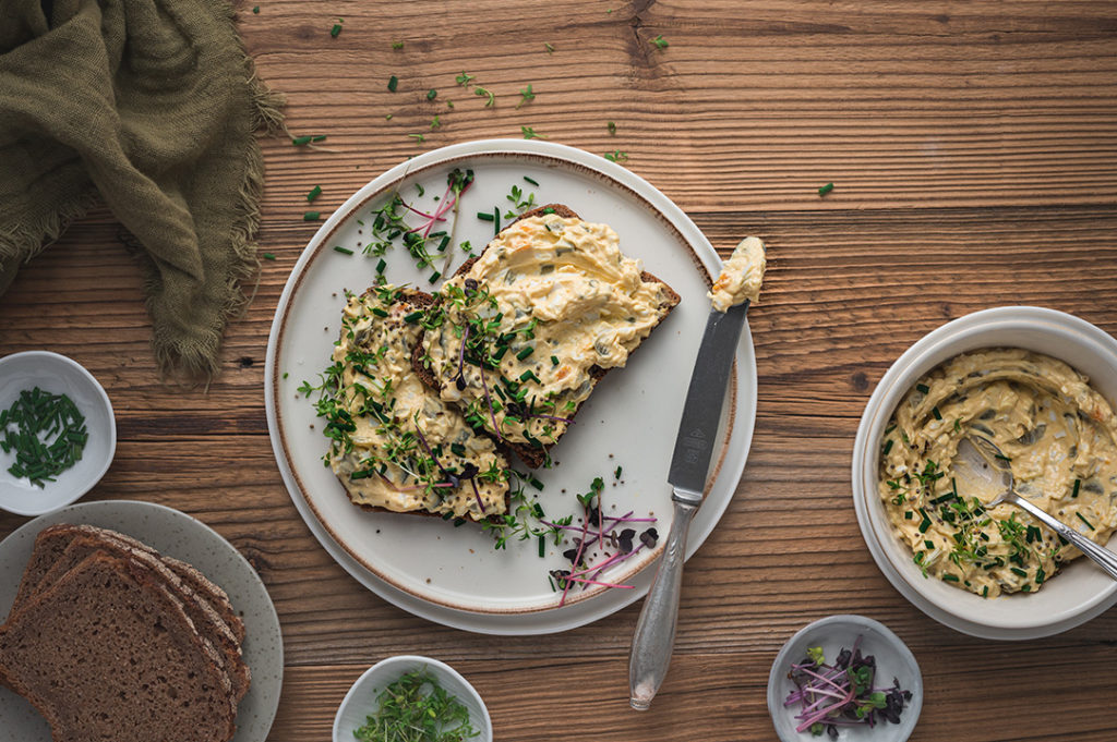 Zwei Scheiben Brot mit herzhaften Eier-Aufstrich belegt liegen auf einem Teller.