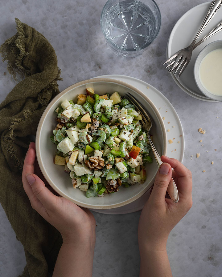 Eine Frau hält eine Schüssel mit Waldorfsalat in ihren Händen.