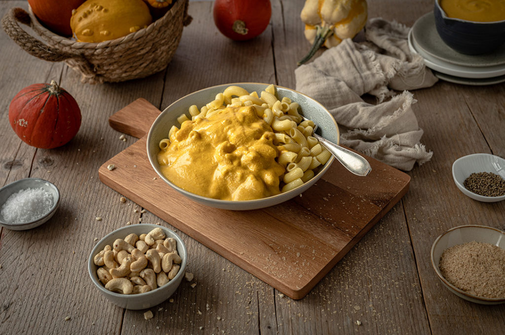 Eine Portion Hörnchennudeln mit veganer Mac and Cheese aus Kürbissuppe steht auf einem Tisch.