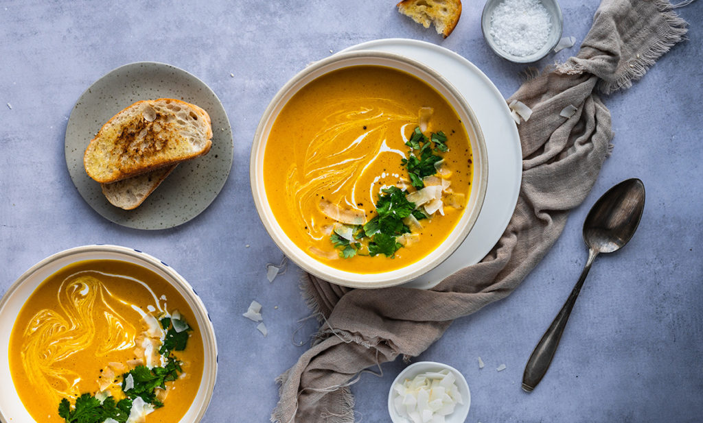 Zwei Teller mit Kürbissuppe ohne Ingwer stehen auf einem Tisch