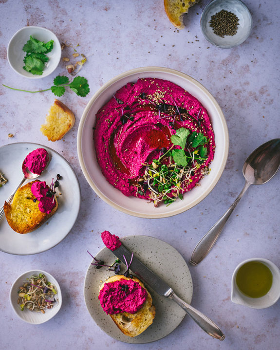 Rote Bete Hummus und geröstetes Brot stehen auf einem Tisch.