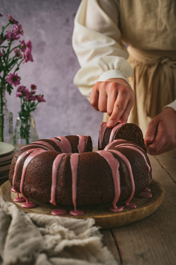 Eine Person nimmt sich ein Stück Rotweinkuchen.