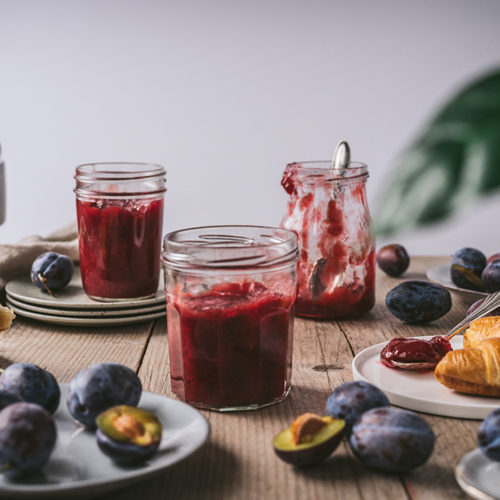 Drei Gläser mit Zwetschgenmarmelade stehen auf einem Tisch