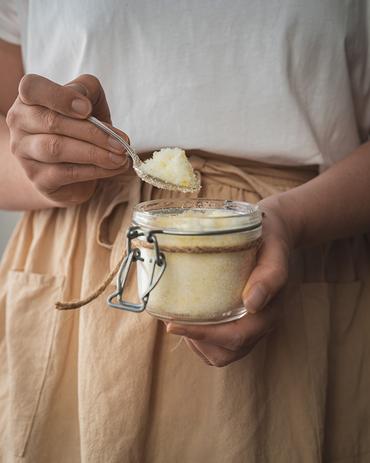 Eine Frau hält ein Weckglas mit Zitronenzucker in der Hand.