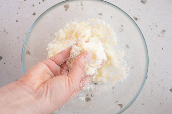 Eine Person vermengt den Zucker mit dem Zitronenabrieb.