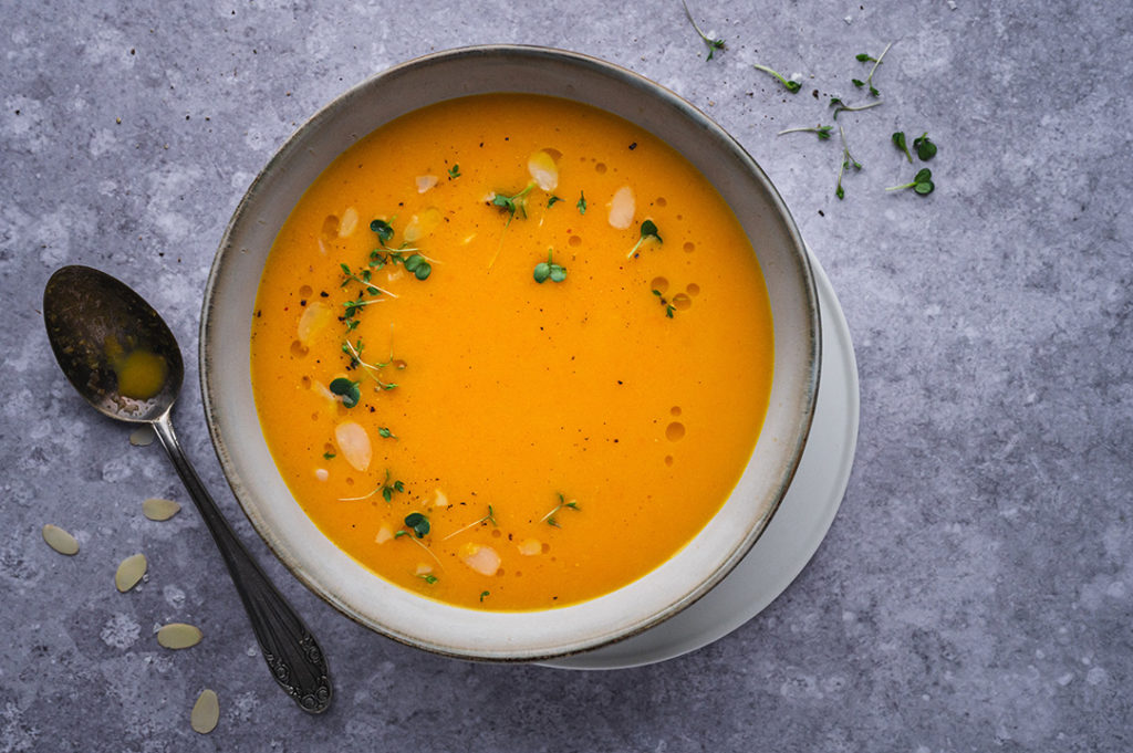 Eine Schüssel mit Karotten-Orangen-Suppe ohne Ingwer steht auf einem Tisch.