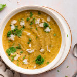 Eine große Schale mit Suppe aus geröstetem Ofengemüse steht auf einem Tisch.