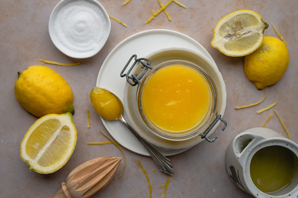Ein Glas mit selbstgemachten Lemon Curd steht auf einem Tisch.