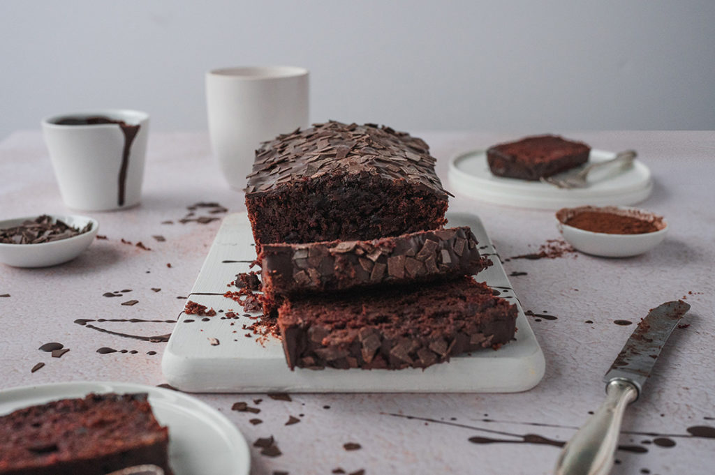 Ein angeschnittener Rote Bete Schokokuchen steht auf einem Tisch.