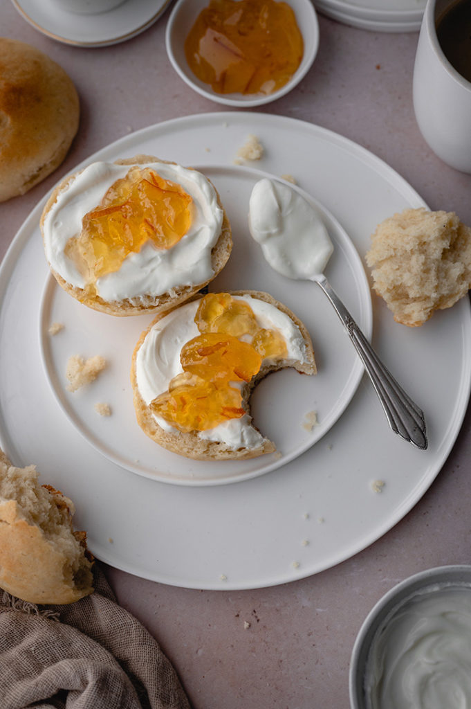 Süße Quarkbrötchen, Tee und Marmelade stehen auf einem Tisch. 