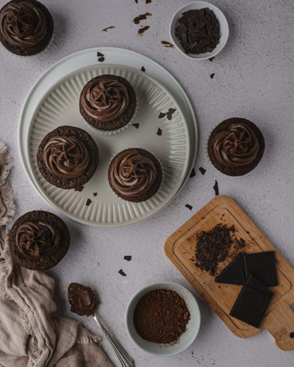 Vegane Schoko-Cupcakes mit Buttercreme verziert auf einem Teller.