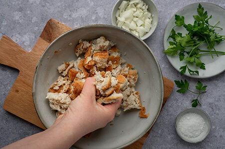 Eine Person drückt das eingeweichte Brot mit den Händen aus.