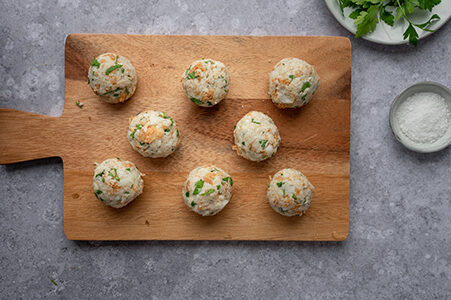 Die fertig geformten Brotfrikadellen liegen auf einem Brett.