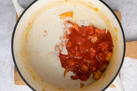 Die gehackten Tomaten und die Kokosmilch ebenfalls in den Top gegeben.