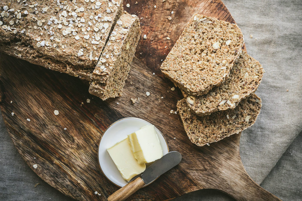 Das angeschnittene Vollkornbrot aus der Kastenform liegt auf einem Brett.