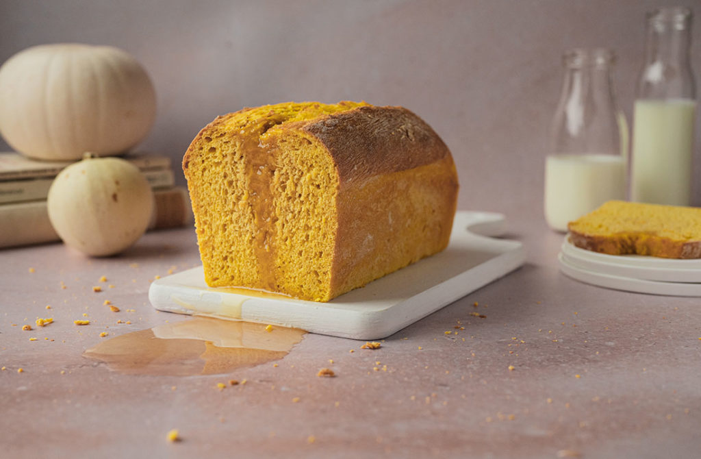 Ein angeschnittenes veganes Kürbisbrot steht auf einem Tisch