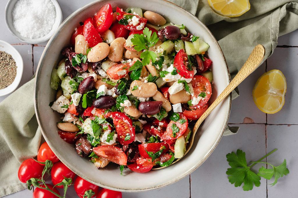 Eine große Schüssel mit griechischem Bohnensalat steht auf einem Tisch.