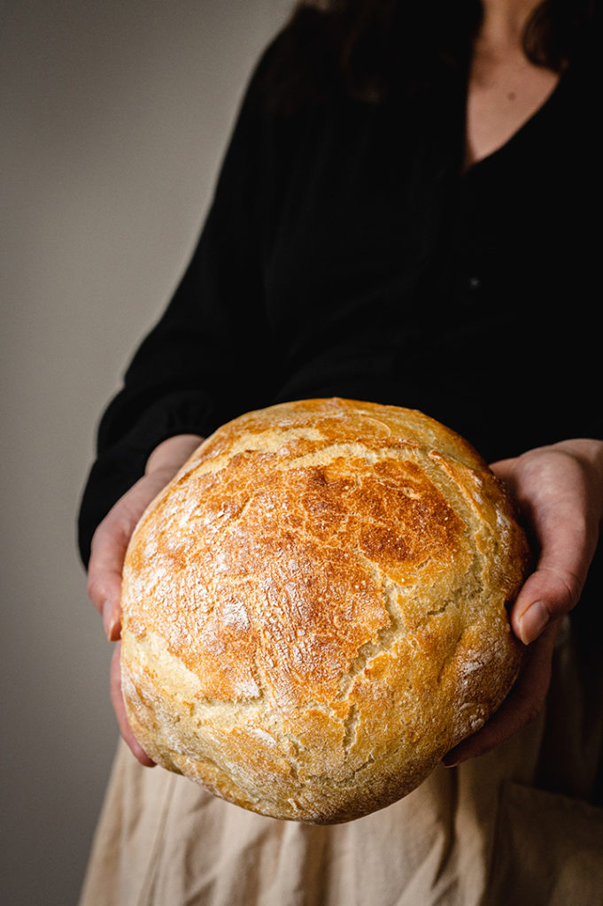 Eine Frau hält das Kartoffelbrot in den Händen.