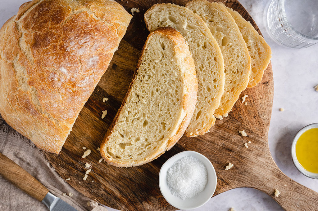 Ein aufgeschnittenes Kartoffelbrot liegt auf einem Brett.