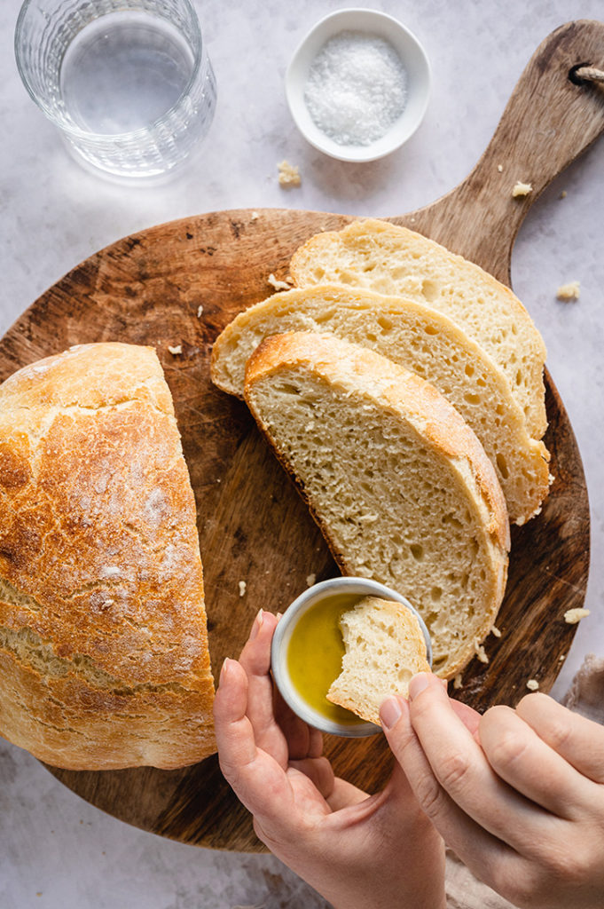 Eine Person tunkt das Brot in Olivenöl.