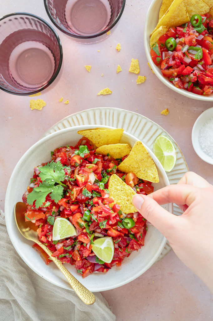 Eine Person dippt Nachos in die Salsa.