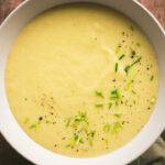 Eine große Schüssel mit Kartoffel Lauch Suppe steht auf dem Tisch.