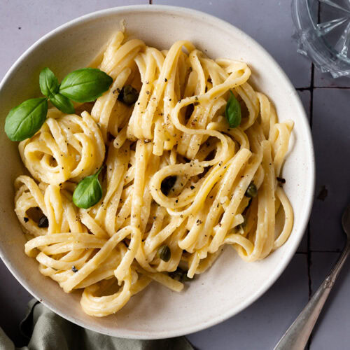 Ein Teller mit vegetarischer Spaghetti Carbonara steht auf einem Tisch.