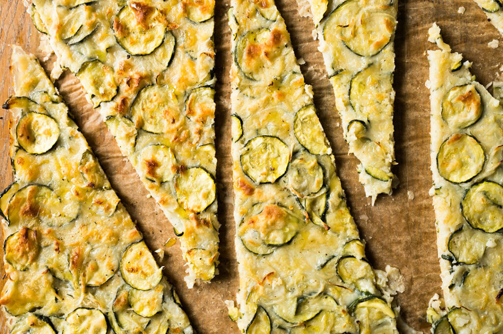 Die fertige Zucchini Scarpaccia wird in Stücke geschnitten.