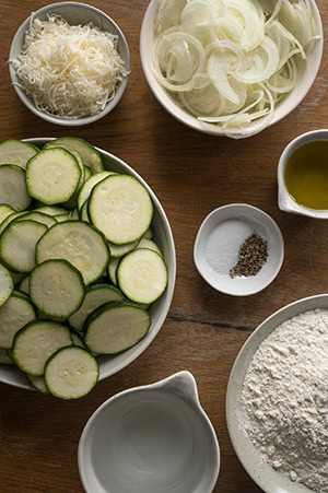 Die Zutaten, um die Zucchini verarbeiten zu können, stehen auf dem Tisch.