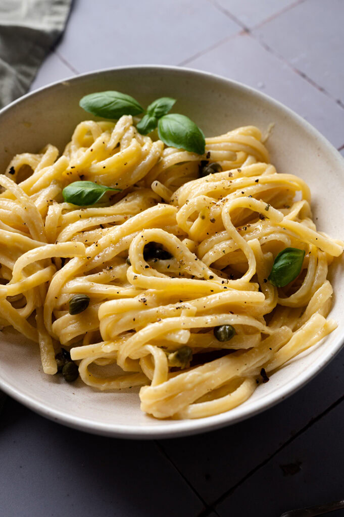 Eine Schüssel mit vegetarischer Spaghetti Carbonara steht auf dem Tisch.