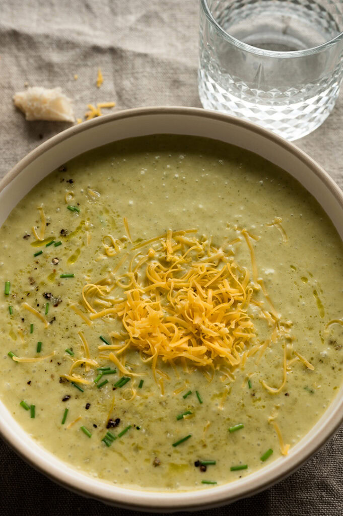 Eine große Schüssel mit Brokkoli Cheddar Suppe steht auf dem Tisch. 